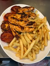 Grilled chicken served with chips and roasted tomato at Tasty Cafe